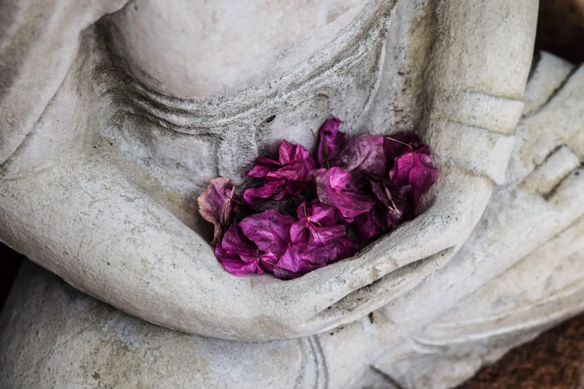 a grey statue holding flowers.